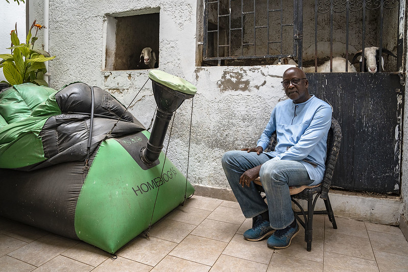 El ingeniero agrónomo senegalés, Lamine Ndiaye, posa junto al biodigestor doméstico que tiene instalado en su hogar en Dakar (Senegal). Lamine colabora con el proyecto de biogás del Pacto de los Alcaldes de África Subsahariana por el clima, financiado por la AECID en Pikine (Senegal). Foto: AECID/Marta Moreiras
