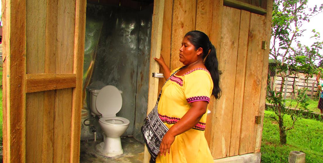 Una mujer de la comarca Ngäbe-Buglé en Panamá muestra los retretes instalados