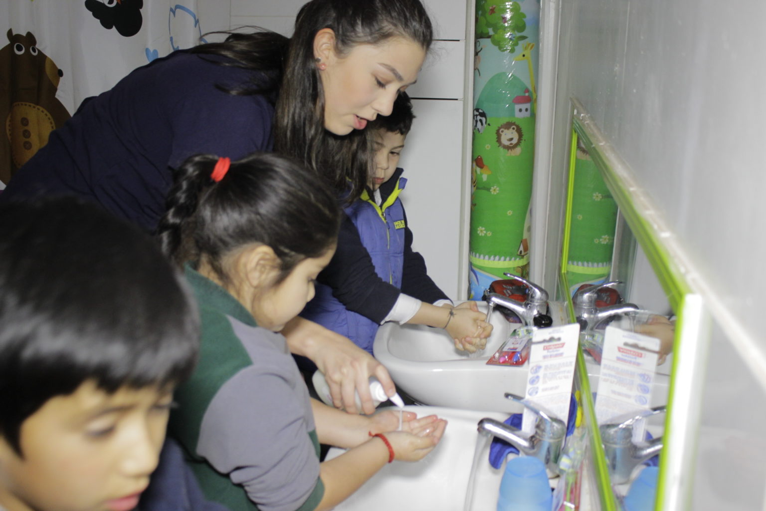 Mujer ayudando a unos niños a lavárse las manos