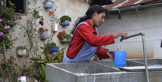 Mujer sacando agua de fuente