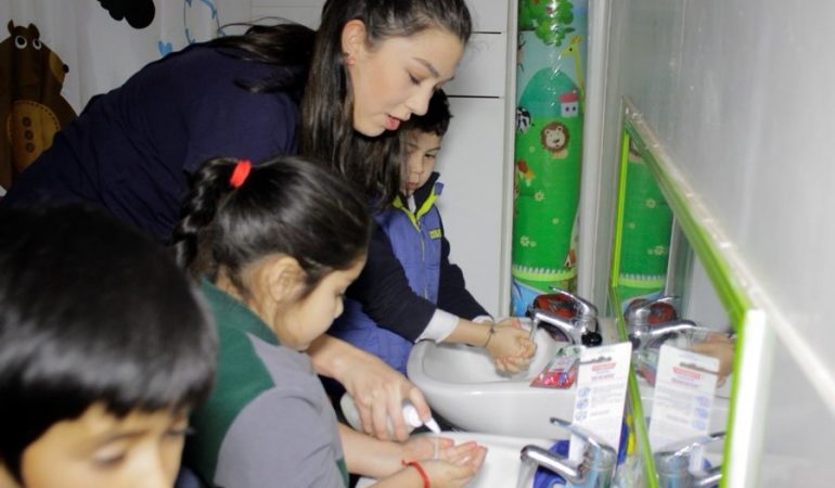 Niños con mujer adulta lavándose las manos