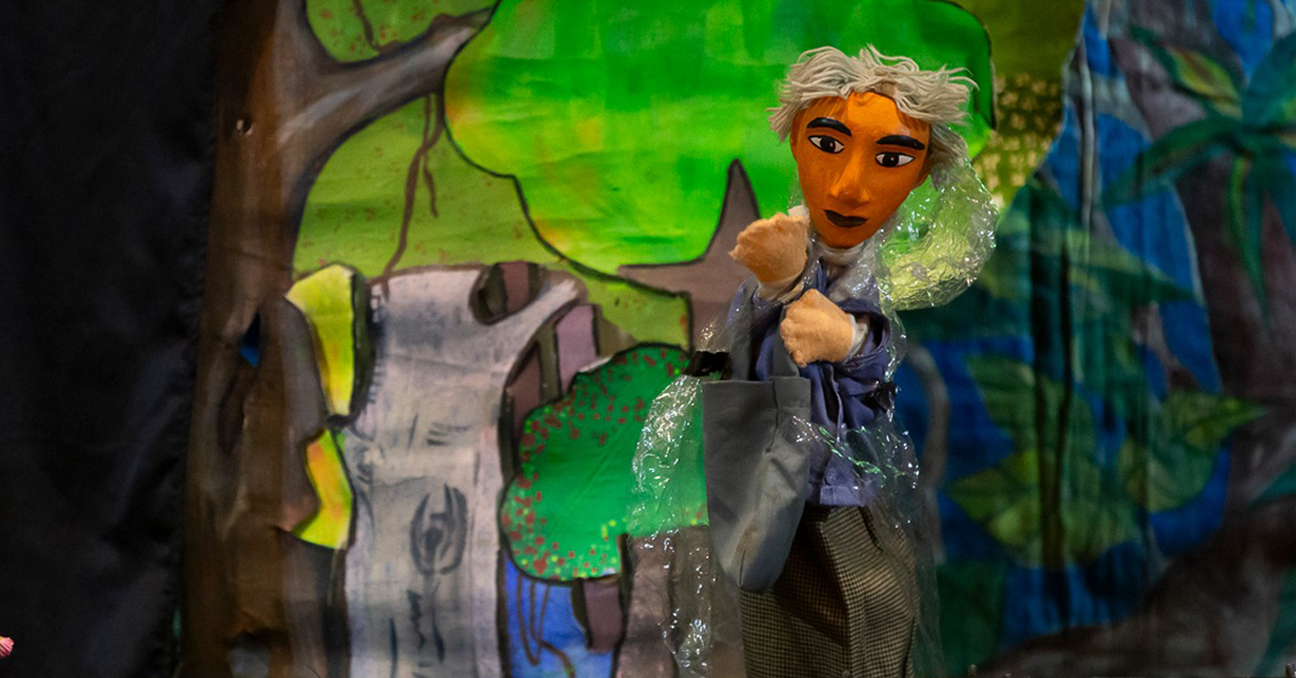Uno de los títeres protagonistas de la obra "El hombre hacha" aparece en un bosque creado dentro del teatrino.