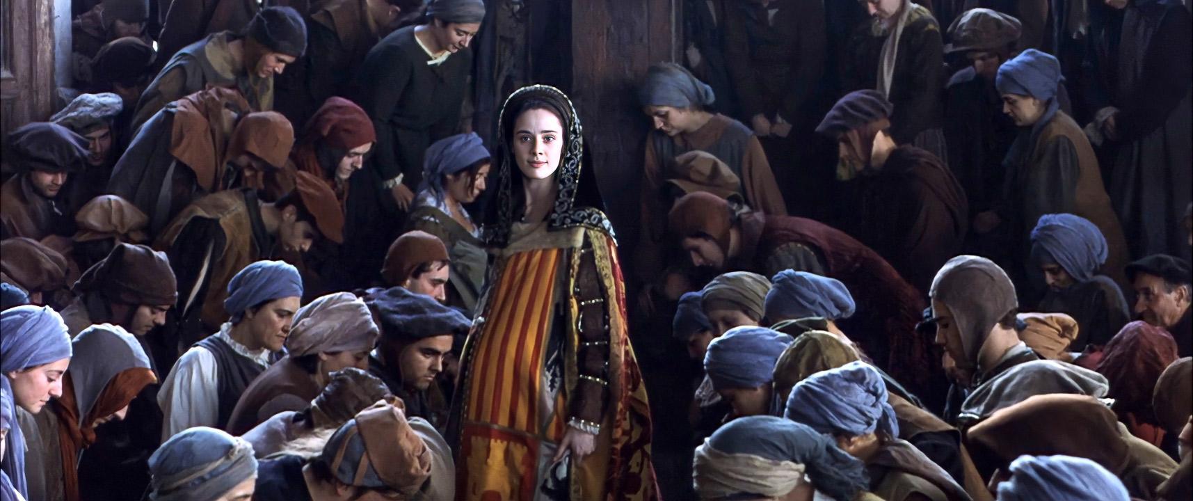 Foto de una escena medieval que muestra a una joven embarazada, vestida con ropa de reina, que está parada en medio de una multitud de personas ...