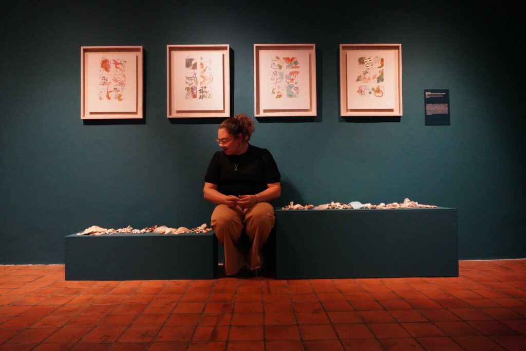 Maga González sentada en sala de exposición 