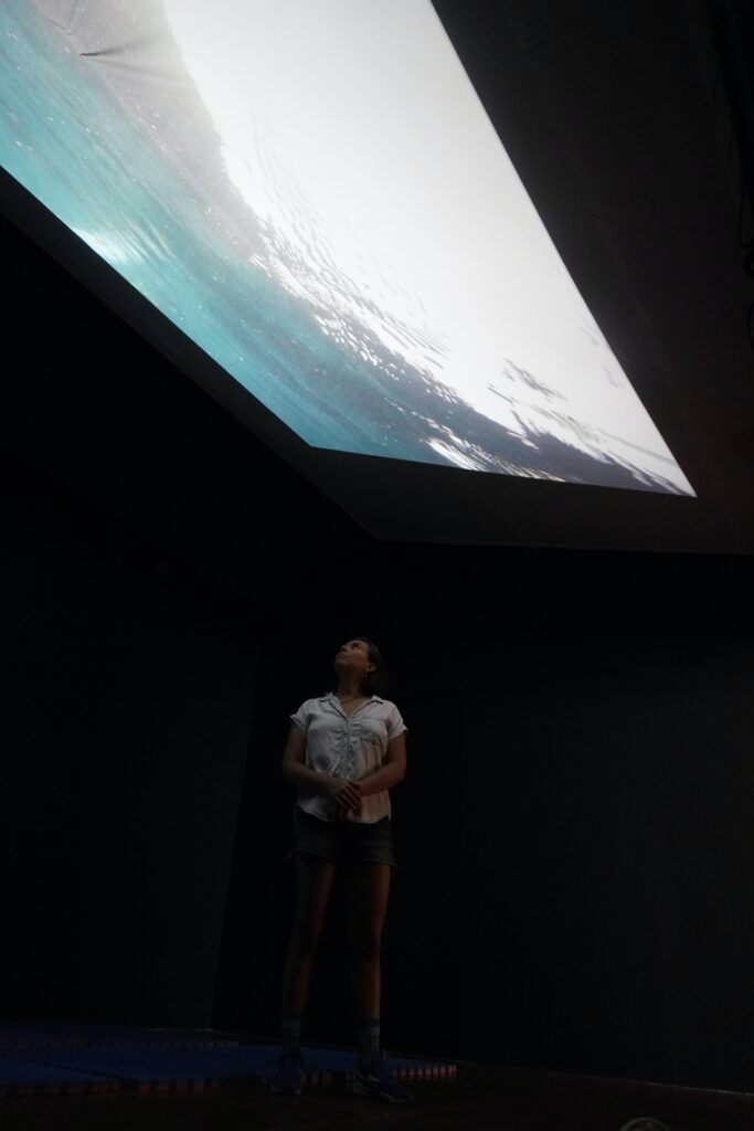 Laura Cruz mirando su obra hacia el techo de la sala