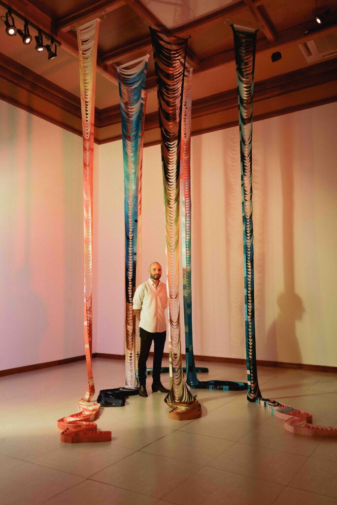 Ale Rambar junto a su obra de columnas de colores