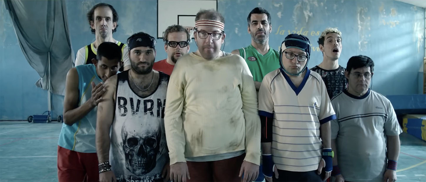 Foto de un grupo de personas con discapacidad intelectual, vestidos con distintas ropas de deporte. Están junto a su entrenador, que es una persona sin discapacidad aparente.