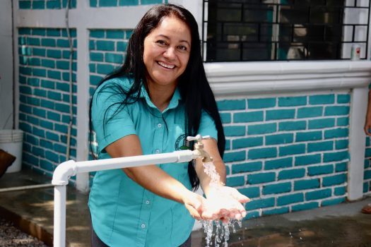 Mujer mostrando como sale agua por ggrifo
