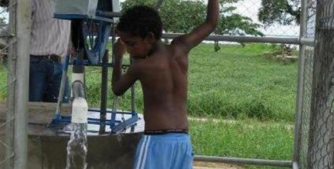 Niño nicaragüense llenando cubo de agua