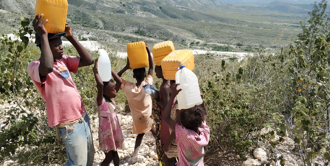 Una familia carga bidones de agua en Haití