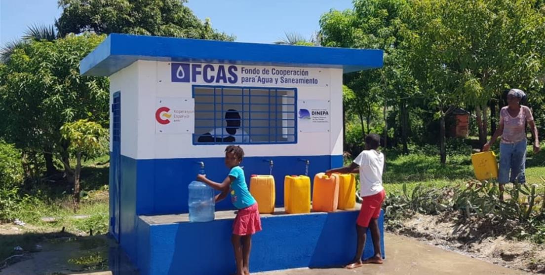 niña recoge agua en kiosko financiado por AECID